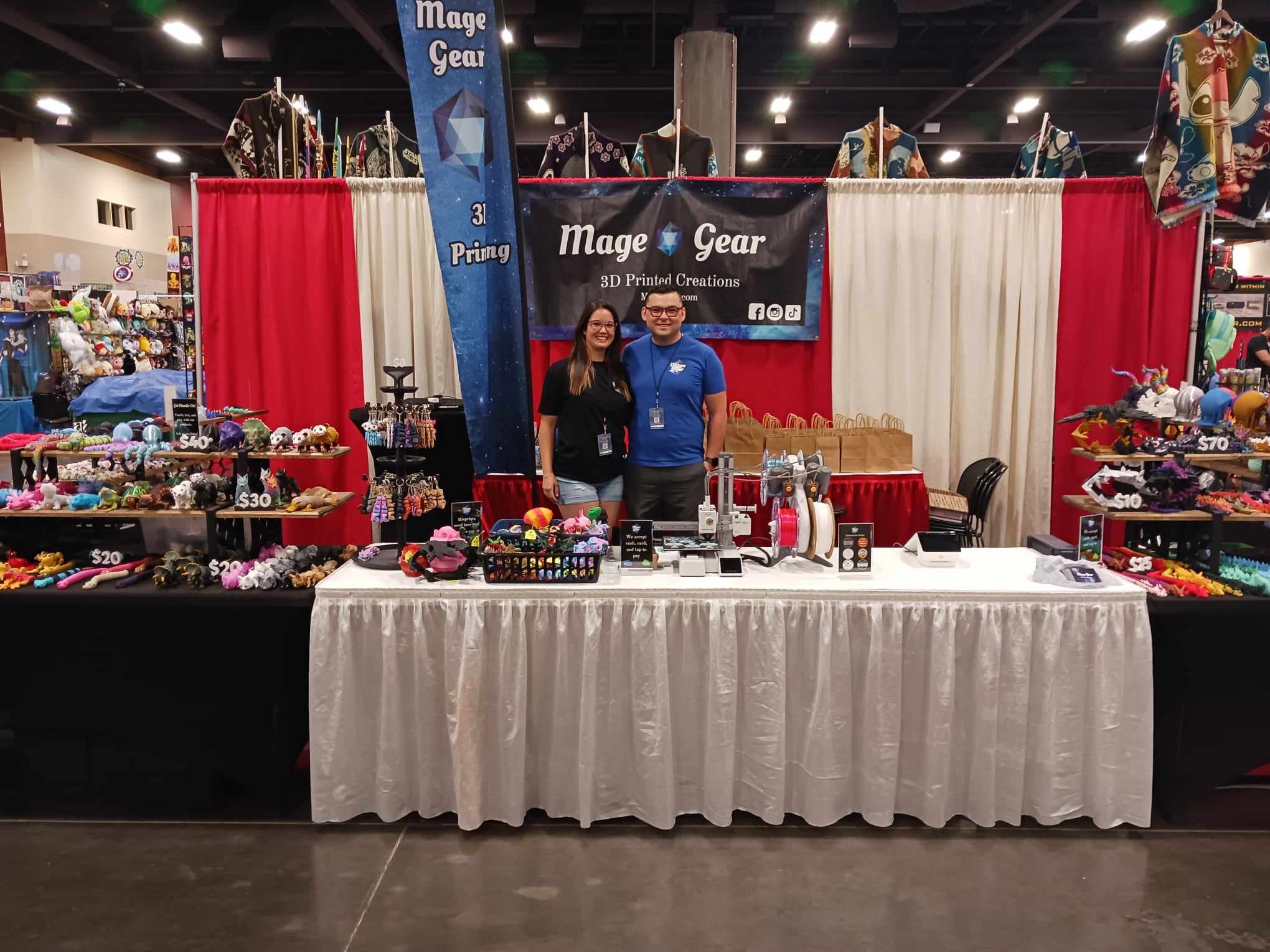 Mage Gear booth at a craft fair — Victor and Jennifer with their full product display